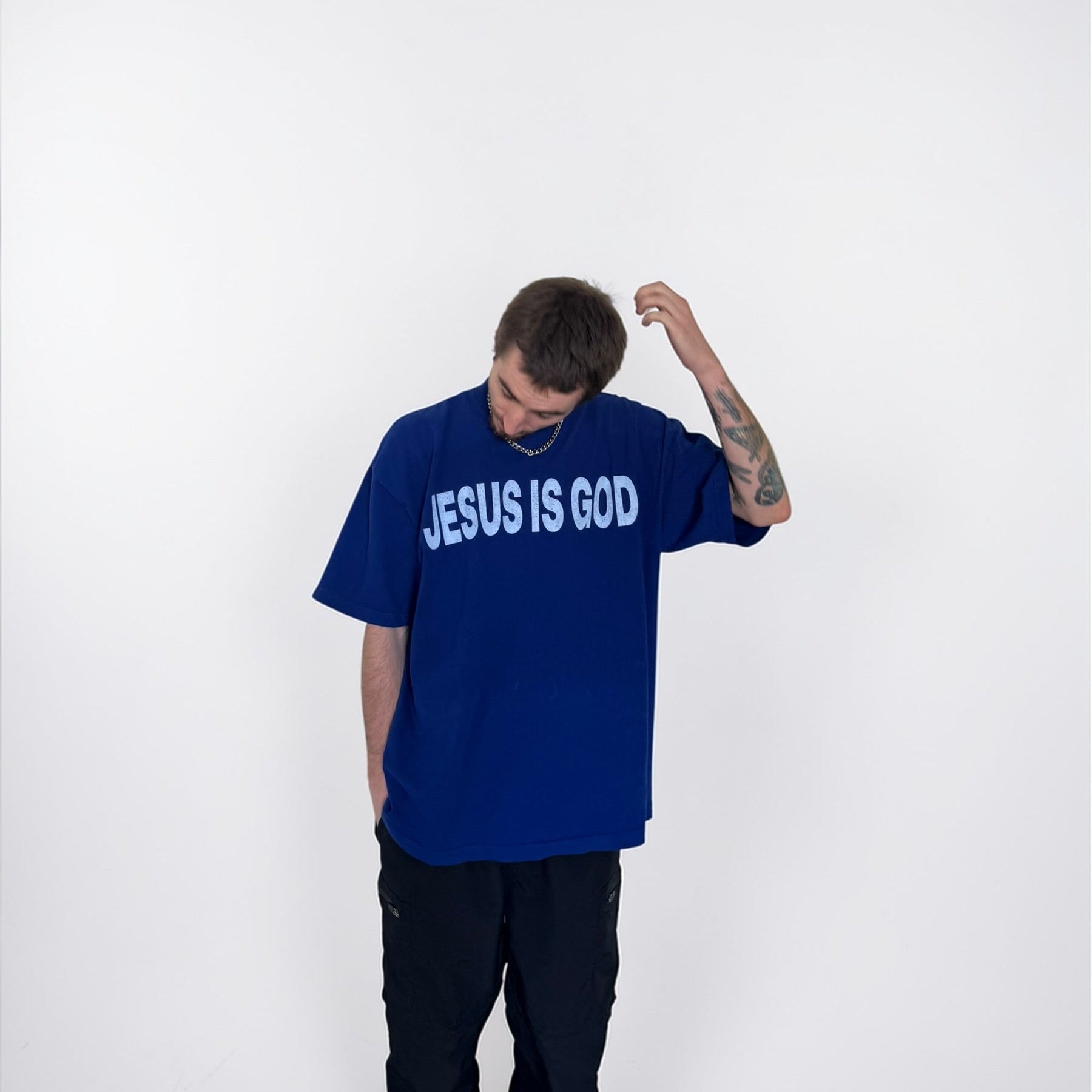Person wearing a blue t-shirt with 'JESUS IS GOD' text on a white background